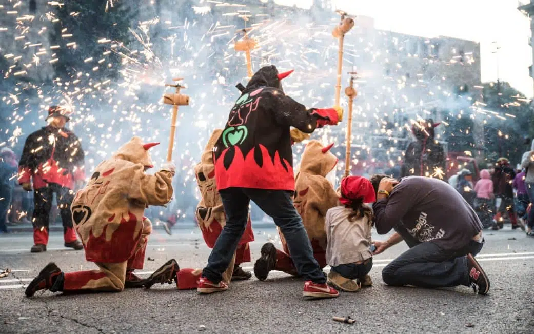 children take cover from the fire of a corre foc fire run at the merce festival in barcelona spain