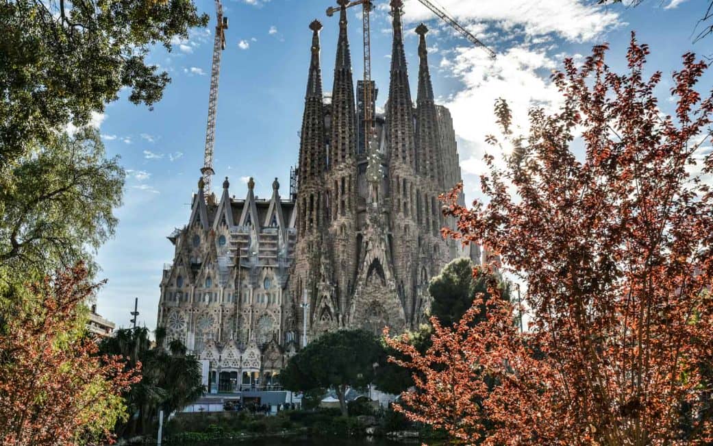 the nativity façade of sagrada familia from across the pond at dusk in barcelona