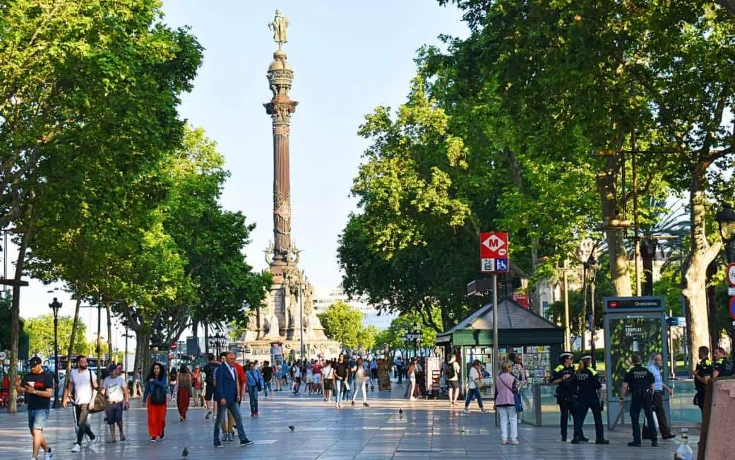 tourists walking along la rambla with columbus statue in the background