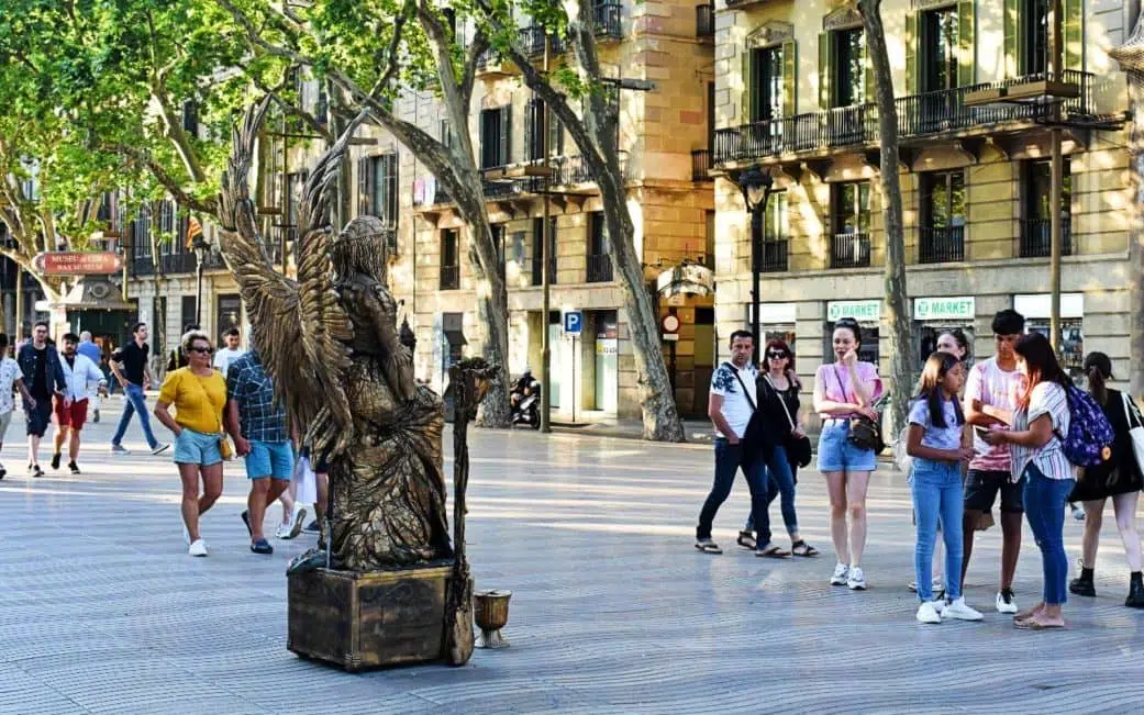 tourists looking at a golden angel street performer on las ramblas barcelona