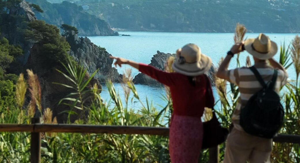 tourists taking pictures of a rocky cove on the costa brava near barcelona spain