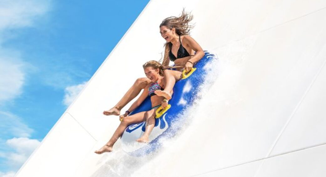 a pair of girls descend down a water slide at marineland catalunya near barcelona