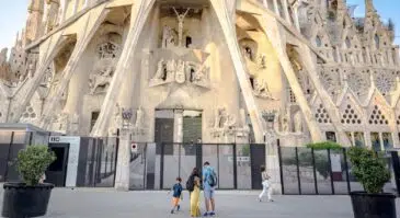 visitors standing outside of the passion facade of sagrada familia at sunset in barcelona