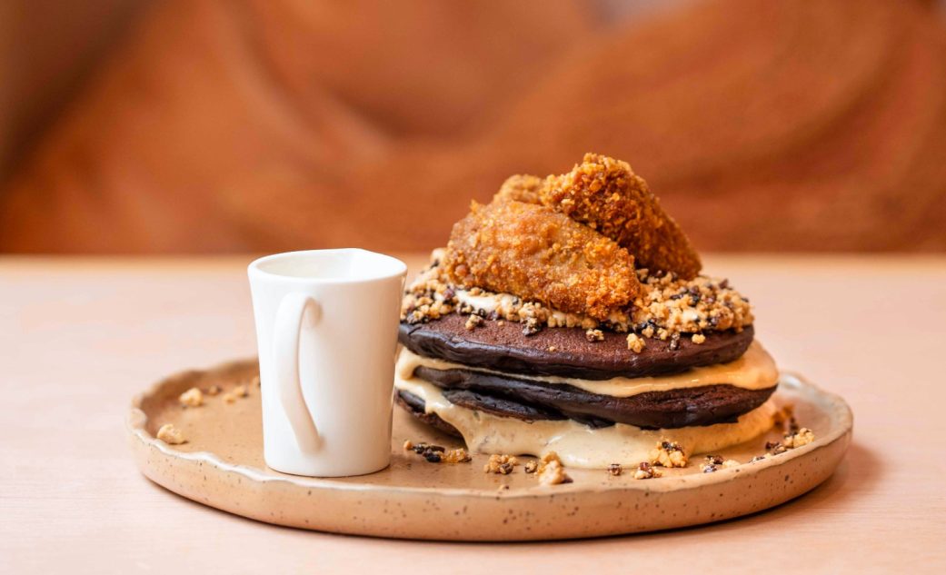 a plate with a stack of chocolate pankcakes and cream with a crumbly topping at the egg lab brunch in barcelona